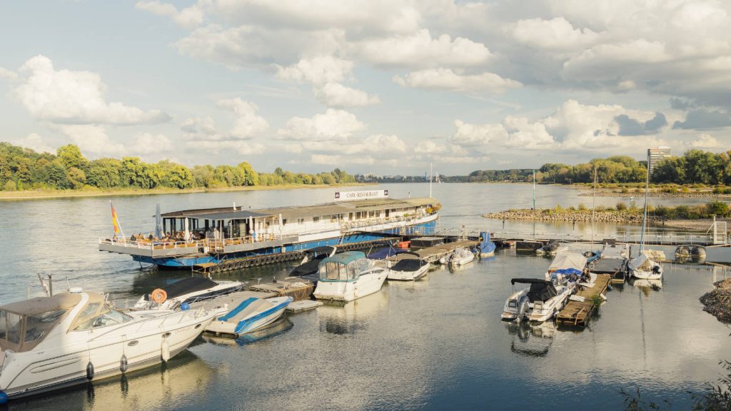 Blick auf ein Restaurant am Rhein, das von Booten umgeben ist