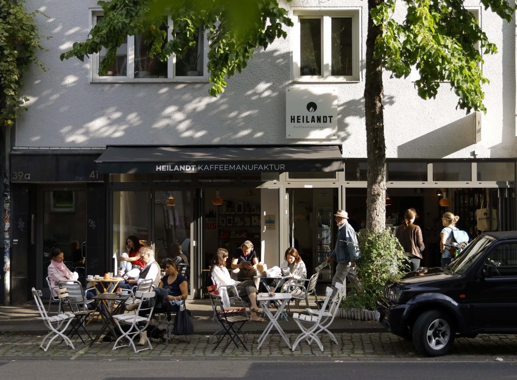 Die Heiland Kaffeemanufaktur ist ein Café in Köln. Gäste haben vor dem Café im Belgischen Viertel Platz genommen
