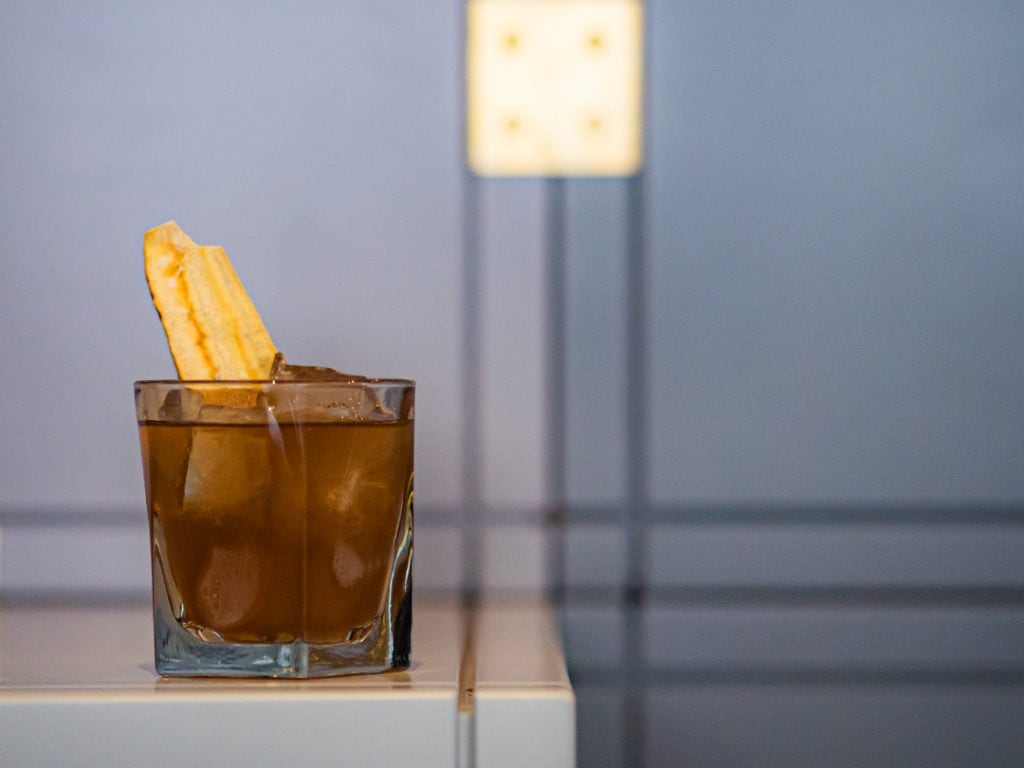 Ein dunkler Cocktail in einem Whiskey-Glas mit Deko und Eis