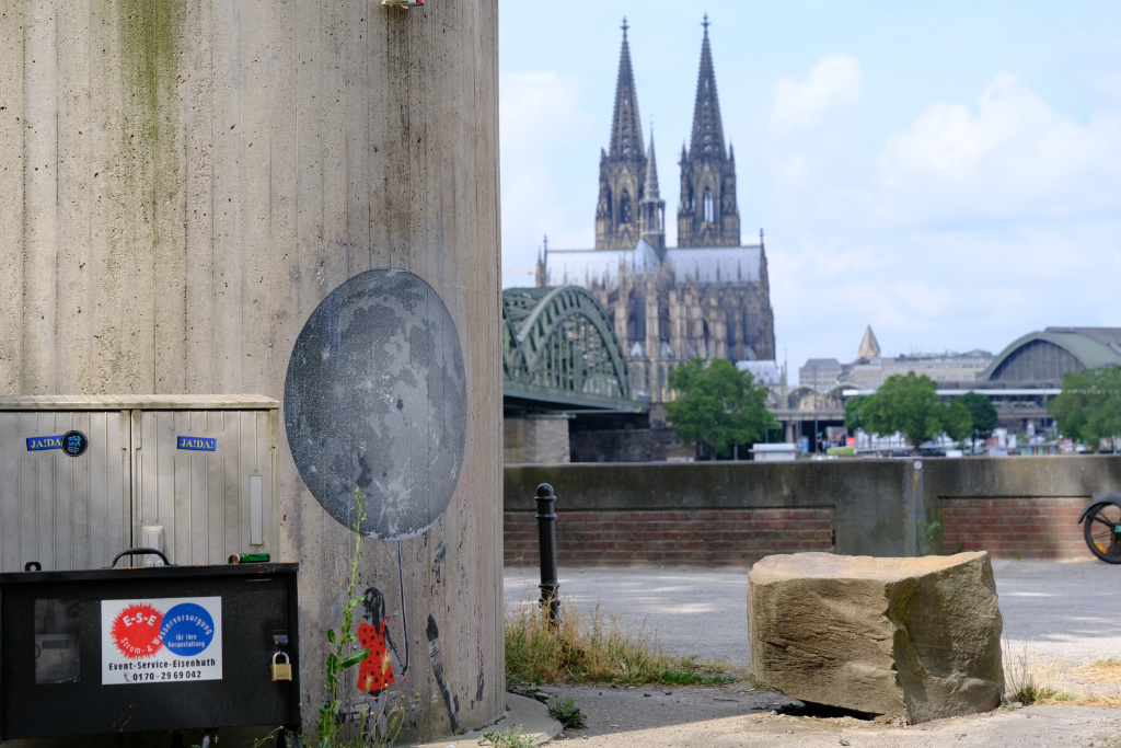 Street Art von Sei Leise neben einem Stromkasten. Im Hintergrund der Kölner Dom