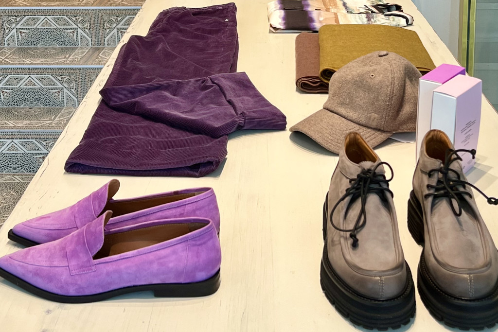 Schuhe, Hosen und Accessoires liegen auf einem Boutique-Tisch.