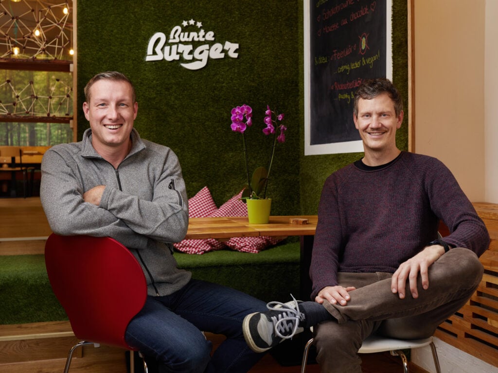 Die Eigentümer von Bunte Burger Köln, Ulrich Glemnitz und Mario Binder sitzen in ihrem Restaurant. 2020 wurden sie mit dem METRO Preis für nachhaltige Gastronomie ausgezeichnet. Foto: Jan Voth