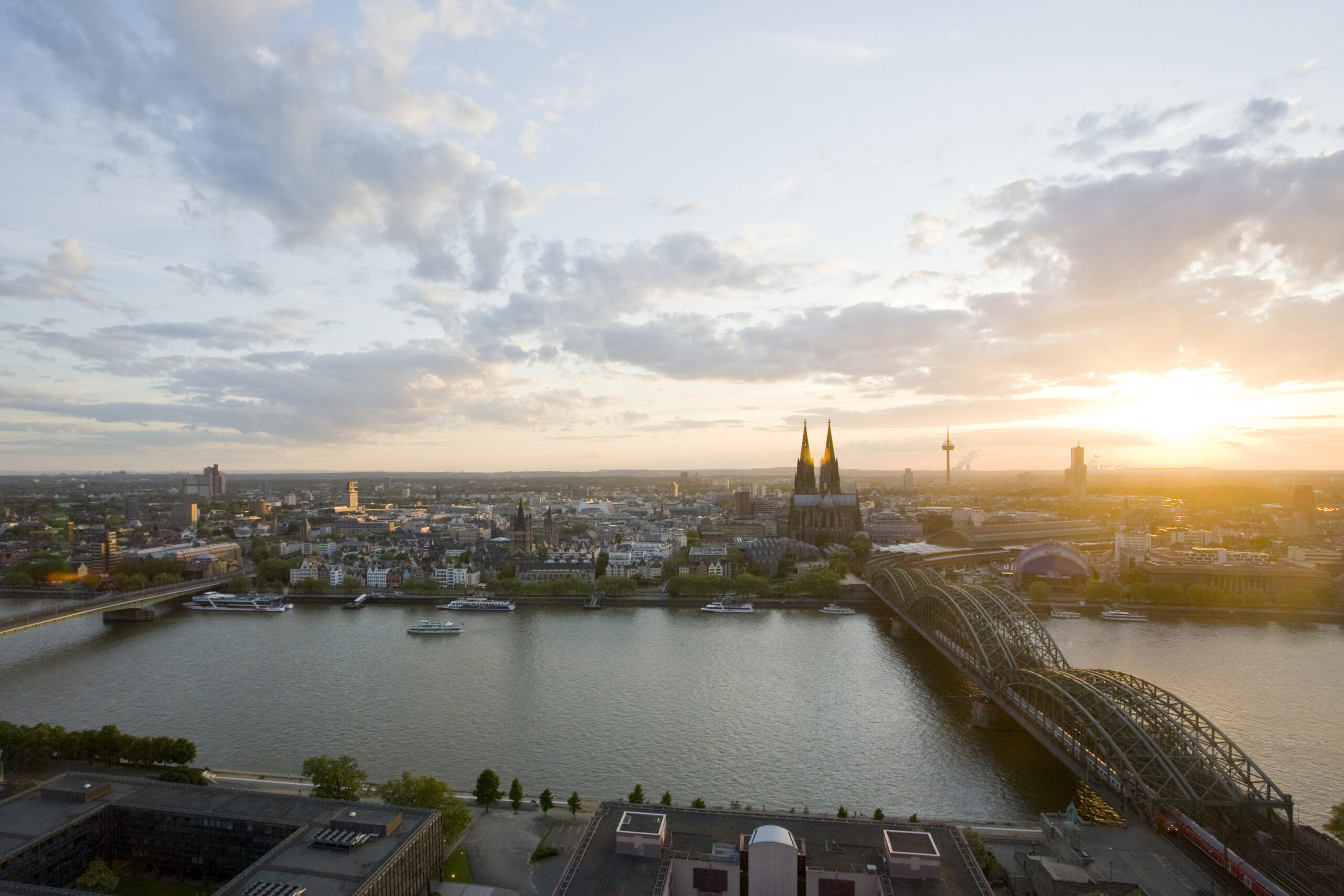 Blick auf den Kölner Dom bei Sonnenuntergang mit der Hohenzollernbrücke und der Deutzer Brücke über den Rhein, Köln.